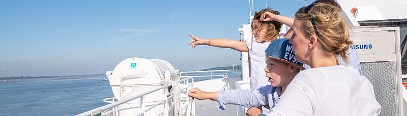 Family on the ship's deck pointing at the sea 